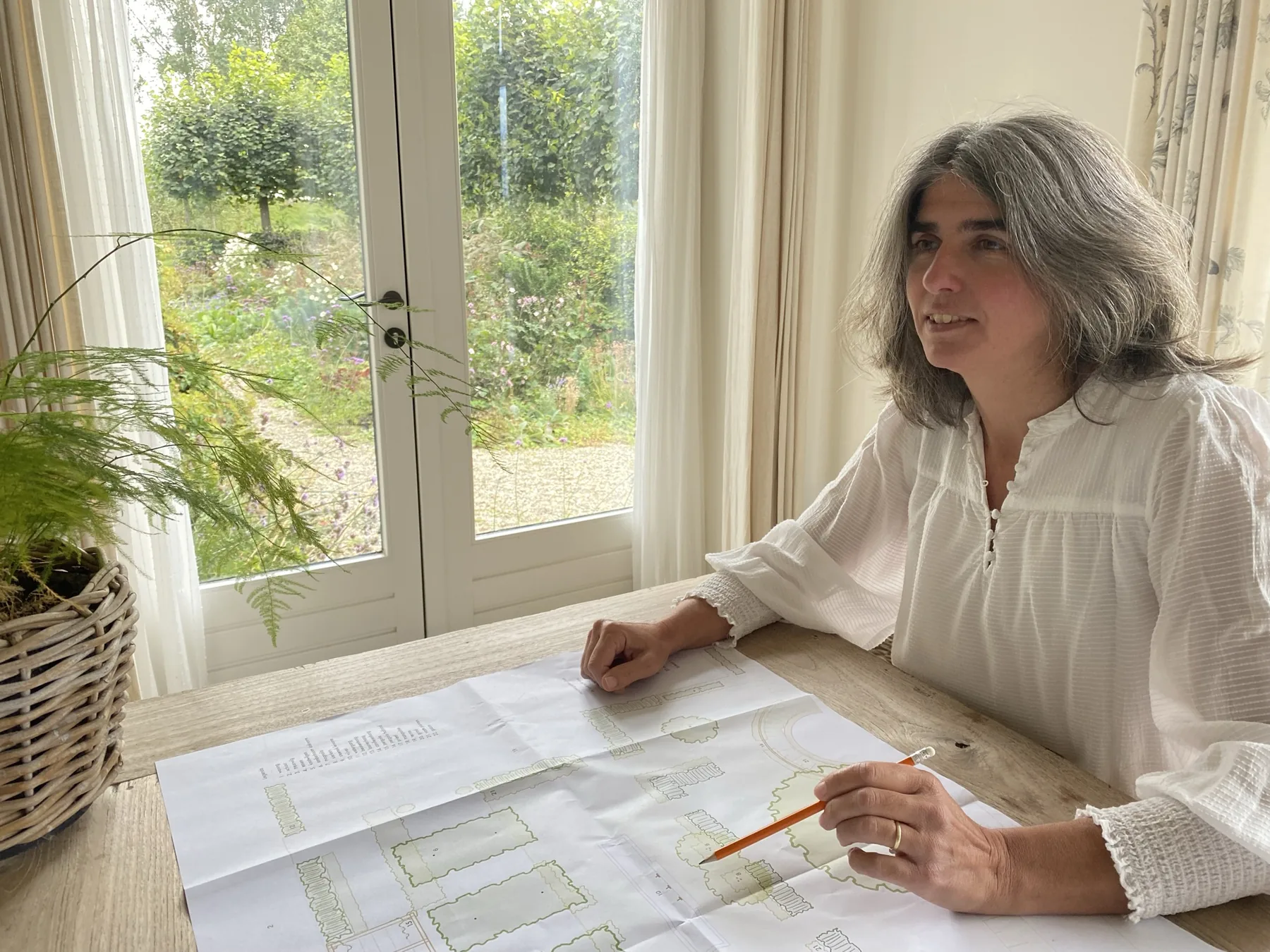 Noortje van Leeuwen werkt aan een tuinontwerp aan tafel.